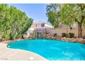 Backyard pool features a rock waterfall and lush landscaping for a tranquil oasis at 10608 Medicine Bow St, Las Vegas, NV 89183