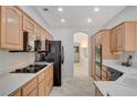 Galley kitchen featuring light wood cabinets, black appliances, and ample counter space at 10025 Netherton Dr, Las Vegas, NV 89134