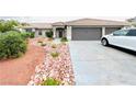 View of front yard with desert landscaping, driveway leading to the garage, and neutral colored exterior at 308 Cannes St, Henderson, NV 89015