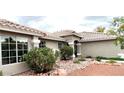 View of the front exterior showcasing its neutral paint, tile roof and beautiful desert landscaping at 308 Cannes St, Henderson, NV 89015