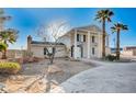Two-story home featuring a grand entrance, palm trees, and rock landscaping at 7477 Ullom Dr, Las Vegas, NV 89139