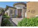 Inviting home entrance with charming patio, desert landscaping, and a cozy seating area at 10057 Regency Canyon Way, Las Vegas, NV 89148