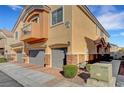 Side view of a home with brick accents, a private balcony, and individual garages at 10074 Aspen Rose St # 101, Las Vegas, NV 89183