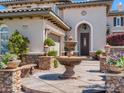 Close-up of an elegant home entrance with a fountain, lush landscaping and stone accents at 2038 Cherry Creek Cir, Las Vegas, NV 89135