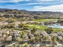 Stunning aerial view of a neighborhood with lush golf course, water features, and mountain views at 1477 Foothills Village Dr, Henderson, NV 89012
