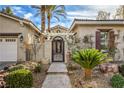 Inviting front entrance featuring an ornate iron gate, lush landscaping, and a decorative pergola at 1477 Foothills Village Dr, Henderson, NV 89012