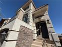 A close-up of the home's front entrance with stone accents, modern lighting, and a private balcony at 7068 Parrot Bay Way, Las Vegas, NV 89118