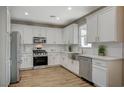 Modern kitchen with stainless steel appliances, white cabinetry, granite countertops, and wood-look flooring at 9601 Rolling Thunder Ave, Las Vegas, NV 89148