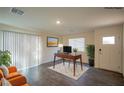 Bright, staged living room featuring hardwood floors, modern desk, and comfortable orange seating at 10079 Dazzling Sunrays Ave, Las Vegas, NV 89129