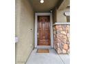 Elegant wood front door framed by stone accents, offering a warm welcome to this lovely home at 10215 Radcliffe Peak Ave, Las Vegas, NV 89166