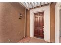 Close-up of the front entrance with a wood door and modern lighting fixture at 1405 San Juan Hills Dr # 104, Las Vegas, NV 89134