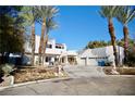 Expansive white home showcasing palm trees, a curved entrance, and a two-car garage at 2010 Mondo Ct, Las Vegas, NV 89123