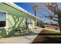 Side view of a charming green home featuring a patio set and a well-maintained yard at 525 Date St, Boulder City, NV 89005