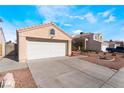 A tan home has a garage and easy-care desert landscaping under a blue sky with scattered clouds at 6224 Mandarin Dr, Las Vegas, NV 89108