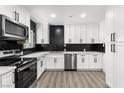 Modern white kitchen featuring sleek cabinets, stainless steel appliances, and black herringbone backsplash at 724 6Th St, Boulder City, NV 89005
