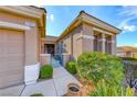 Warm exterior view showcasing the desert landscaping with gate, bushes, and stone-paved walkway at 2069 King Mesa Dr, Henderson, NV 89012