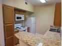 Well-equipped kitchen featuring a white refrigerator, microwave, and an elegant granite countertop at 7255 W Sunset Rd # 1171, Las Vegas, NV 89113