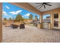 An inviting covered outdoor patio features brick pavers, comfortable seating, and a built-in grill and pizza oven at 2436 Chateau Napoleon Dr, Henderson, NV 89044