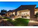 Inviting backyard with a covered patio, outdoor seating, lush grass, and stone accents at 4796 Riva De Romanza St, Las Vegas, NV 89135