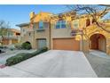 Two-story townhouse features attached garage, desert landscaping, and decorative architectural details at 820 Canterra St # 1054, Las Vegas, NV 89138