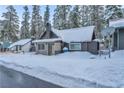 Snow-covered cabin showcases a stone chimney and cozy aesthetic nestled amongst towering pine trees at 4587 Yellow Pine Ave, Mount Charleston, NV 89124