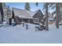 Dark brown cabin has snow-covered landscape, cozy awning, and quaint design in a serene winter setting at 4587 Yellow Pine Ave, Mount Charleston, NV 89124