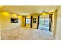 Bright and airy living room with plush carpeting, large windows, and sliding glass door to the outside at 4488 Mission Meadow Cir, Las Vegas, NV 89139