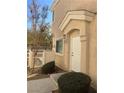 Inviting front exterior featuring an arched entryway, white door, and manicured bushes at 8635 Tomnitz Ave # 103, Las Vegas, NV 89178