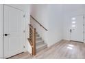 Bright entryway featuring wood-look flooring and an open staircase with modern wood and black metal railings at 11940 Vector Ray Ave, Las Vegas, NV 89138