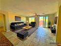 Comfortable living room with plush black seating, warm lighting, and a sliding glass door to the backyard at 1630 Meadow Bluffs Ave, Henderson, NV 89014