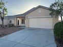 Beige single-story home with a two-car garage and a well-maintained front yard at 6165 Highland Gardens Dr, North Las Vegas, NV 89031
