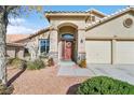 Inviting home featuring desert landscaping, an arched entryway, and a red front door at 688 Quiet Stream Ct, Henderson, NV 89052