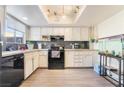 The kitchen features white cabinets, wood floors, and black appliances at 466 Las Casitas Way, Las Vegas, NV 89121