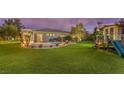 A spacious backyard featuring a pool, patio, playhouse and lush lawn area at 71 Fountainhead Cir, Henderson, NV 89052