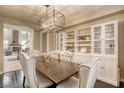 Elegant dining room featuring a stylish chandelier, a dining table with tufted chairs, and custom built-in cabinets at 9950 Waxberry Ct, Las Vegas, NV 89178