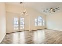Bright living room with wood floors, vaulted ceilings, a ceiling fan, and access to a balcony at 10147 Aspen Rose St # 101, Las Vegas, NV 89183