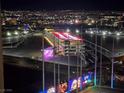 Night view of a multilevel Topgolf facility with an illuminated driving range, against the Las Vegas skyline at 135 E Harmon Ave # 2120, Las Vegas, NV 89109
