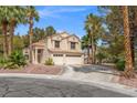 Two-story home featuring a three-car garage, desert landscaping, and mature palm trees at 399 Placer Creek Ln, Henderson, NV 89014