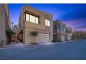 Modern exterior townhome boasting clean lines, neutral tones, attached garages, and landscaping, set against a blue sky at dusk at 9 Promenade Isle Ln, Henderson, NV 89011