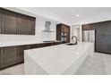 Modern kitchen with dark wood cabinetry, stainless steel appliances, and an island with a white countertop at 9 Promenade Isle Ln, Henderson, NV 89011