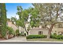 Two-story stucco home featuring a red tile roof and mature landscaping in a suburban neighborhood at 9044 Opus Dr, Las Vegas, NV 89117