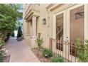 Charming home exterior featuring detailed columns, a small balcony, lush greenery, and a glimpse of the interior staircase at 9044 Opus Dr, Las Vegas, NV 89117