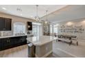 Modern kitchen with dark cabinets, stainless steel appliances, and a large island; dining area nearby at 9835 Fox Estate St, Las Vegas, NV 89141