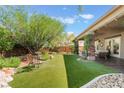 Expansive backyard featuring artificial turf, decorative rock, and a covered patio for relaxing and entertaining at 4014 Trapani Pl, Las Vegas, NV 89141