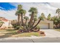 Inviting single-story house showcasing a xeriscaped front yard with palm trees and lush green grass at 5212 Painted Lakes Way, Las Vegas, NV 89149