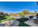 Large manicured backyard featuring a spacious patio with an outdoor kitchen and desert views at 10386 Luna Magico Ave, Las Vegas, NV 89135