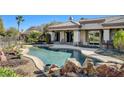 Beautiful backyard oasis with a lagoon-style pool, stone accents, and an outdoor seating area at 10386 Luna Magico Ave, Las Vegas, NV 89135
