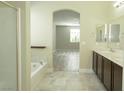 Bathroom featuring dual sinks, a soaking tub, and a separate glass-enclosed shower at 1617 Meadow Bluffs Ave, Henderson, NV 89014