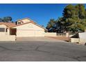 Single-story home with a three-car garage, desert landscaping, and mature shade trees at 4135 Al Carrison St, Las Vegas, NV 89129