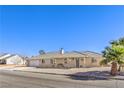 Charming single-story home featuring a gravel yard, palm trees, and a tile roof under a blue sky at 3192 Taylor St, Logandale, NV 89021